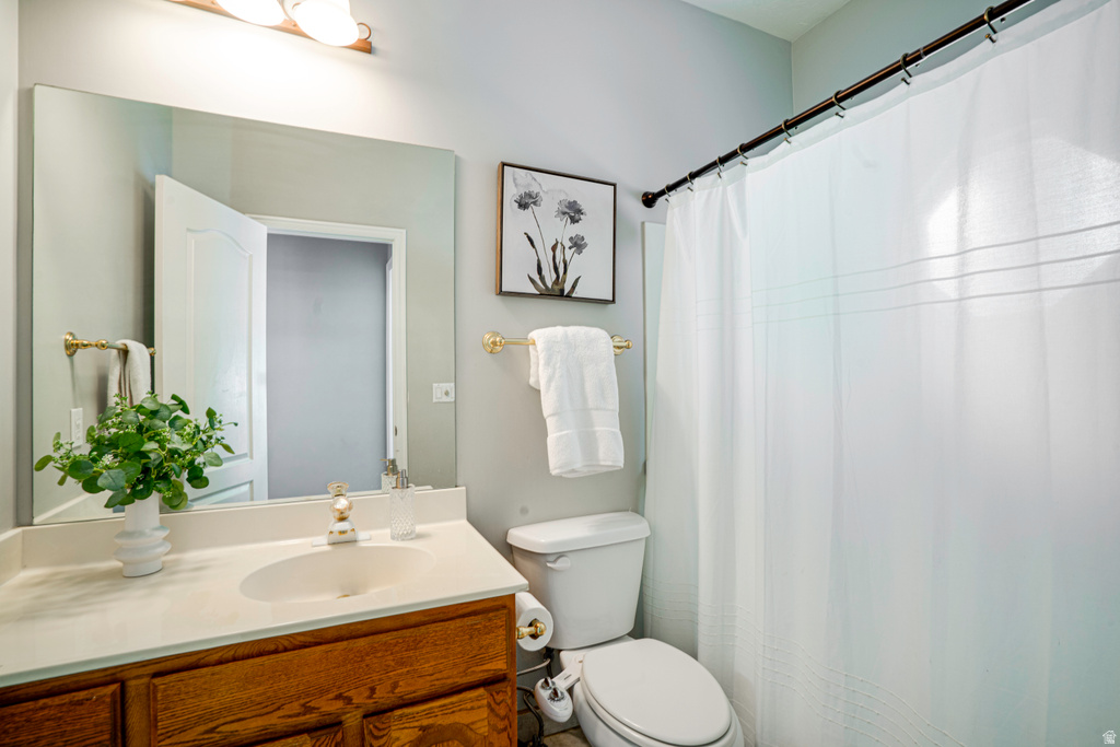 Bathroom featuring a wood-finish vanity with a light-colored countertop, an undermount sink, and a large wall-mounted mirror