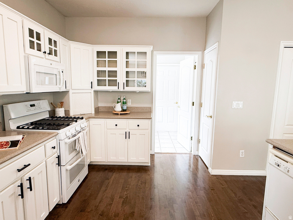 White cabinetry, wood-finish flooring, built-in microwave, gas range, and a built-in dishwasher