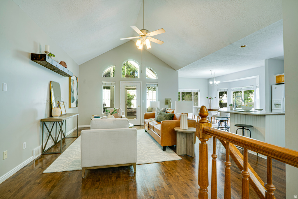 Spacious living area featuring a vaulted ceiling with a ceiling fan, hardwood flooring, and light gray walls