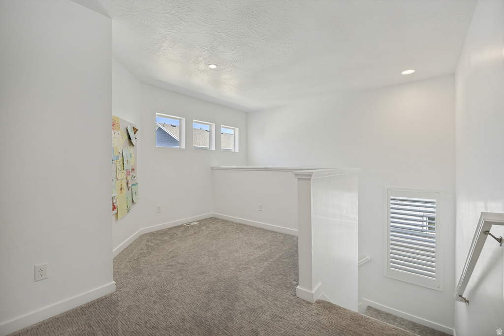 Upper-level landing featuring textured carpeting, white walls, and recessed lighting