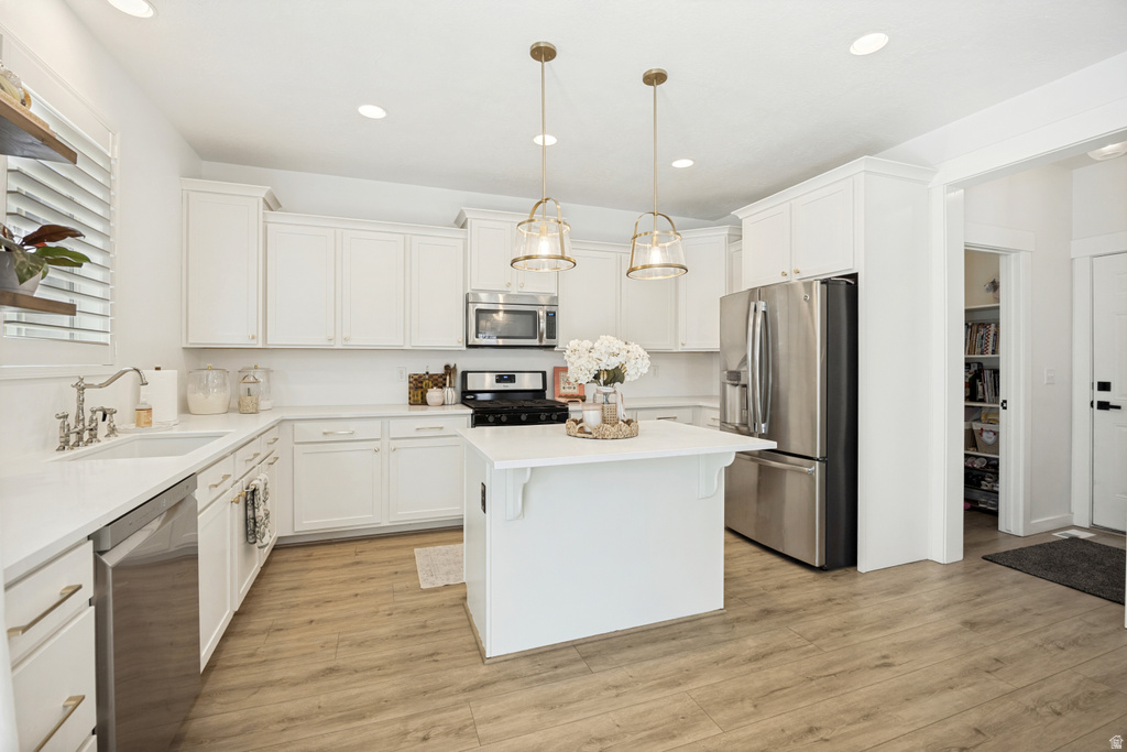 Kitchen featuring white cabinetry, wood-finish flooring, stainless steel appliances, a center island, and recessed lighting