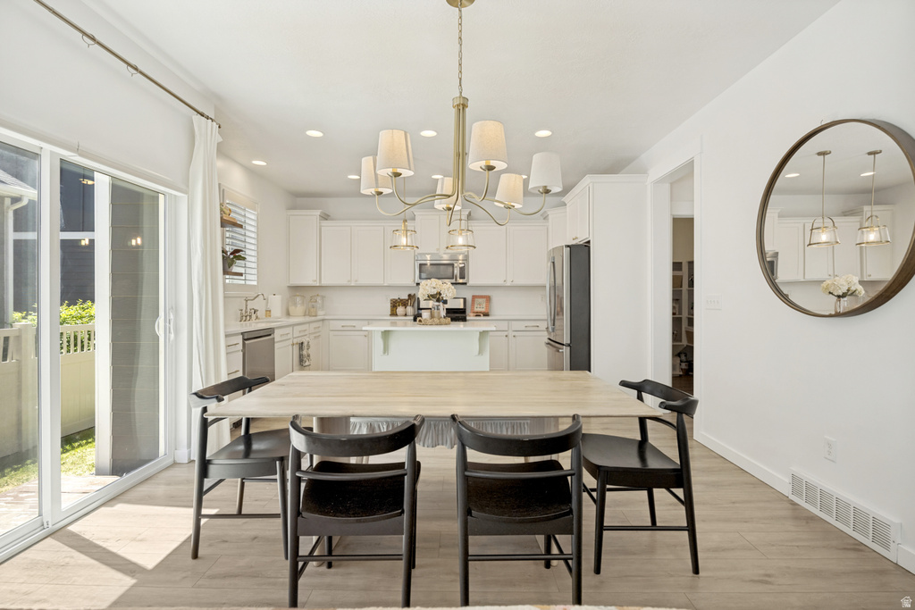 Open-concept dining area featuring wood-finish flooring and a brass chandelier