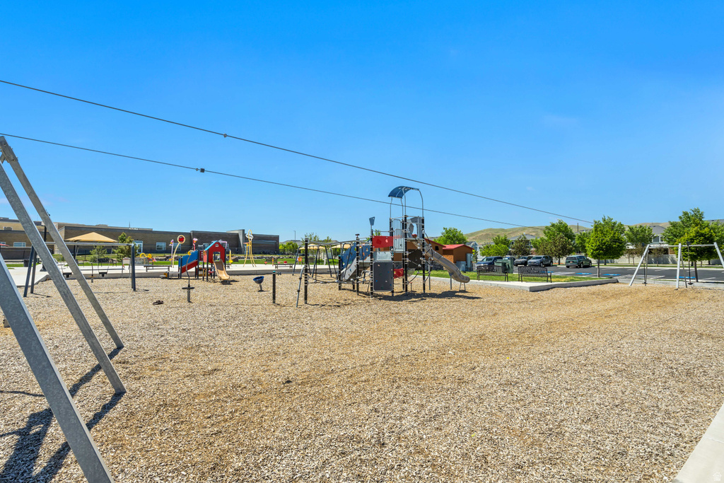 Community playground featuring a wood chip surface, multiple play structures, swings, and a zip line