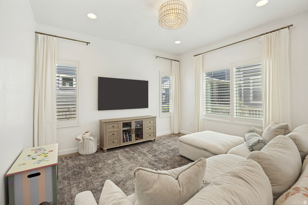 Spacious living area featuring ample natural light from multiple windows, recessed lighting, a decorative ceiling fixture, and neutral wall tones