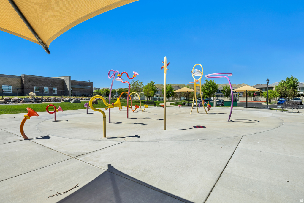 Community splash pad with colorful water features, surrounding concrete surfacing, and shade structures