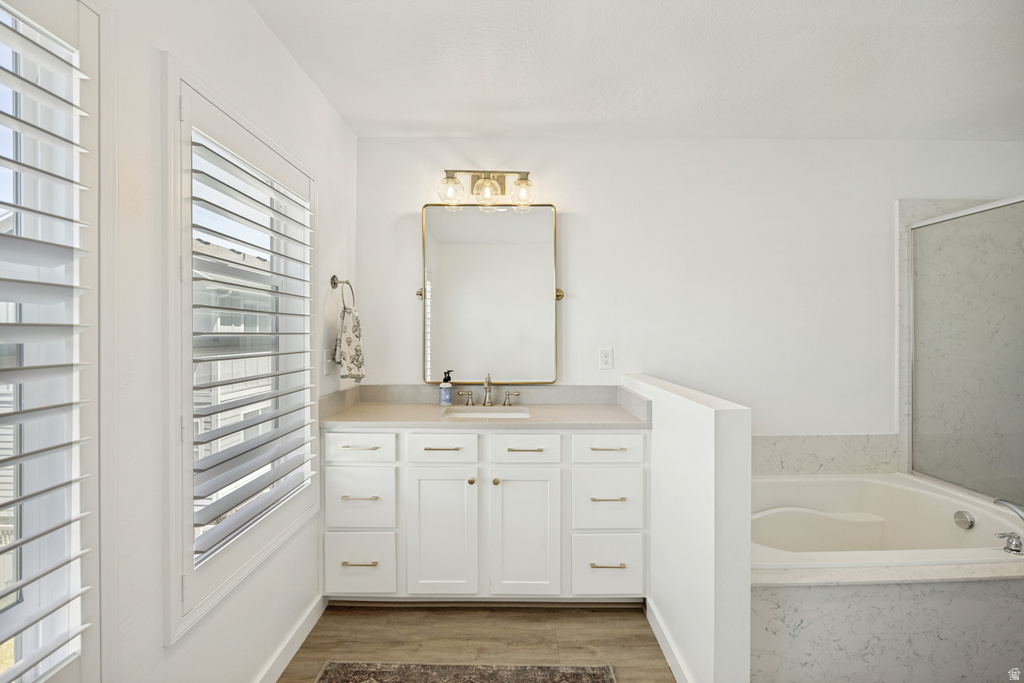 Bathroom featuring a single vanity with white cabinetry, light-toned countertop, and gold-finish hardware