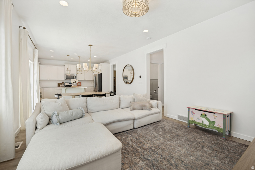 Open-concept living space featuring wood-finish flooring, recessed lighting, and a contemporary chandelier