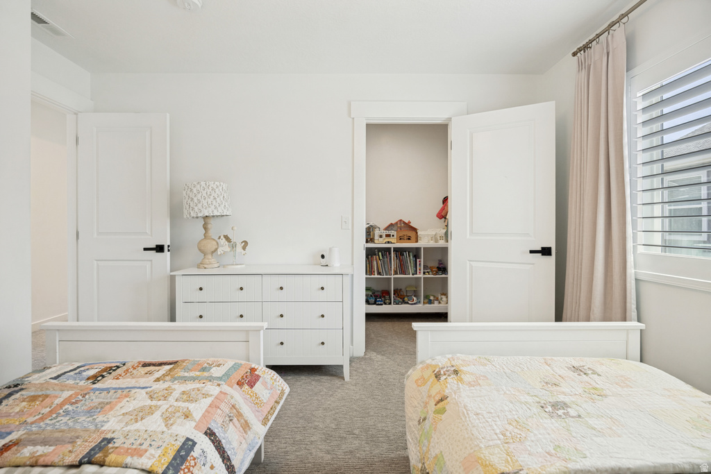 Room featuring neutral wall tones, two white paneled doors with black hardware, and a window with white louvered shutters and a fabric curtain
