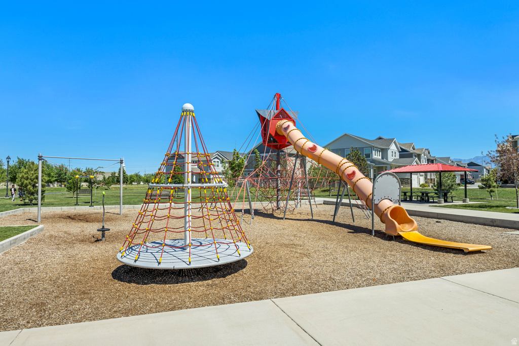 Community playground featuring a rope climbing structure, a covered slide, and swing sets