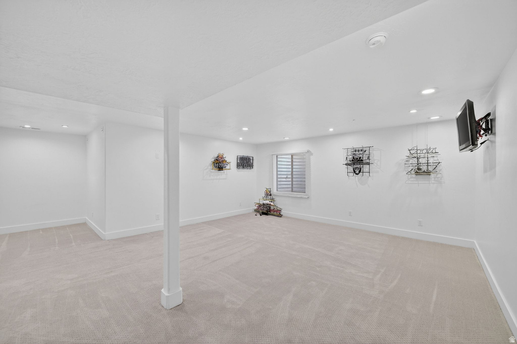 Spacious room featuring light-toned carpet flooring, recessed lighting, and a window with horizontal blinds