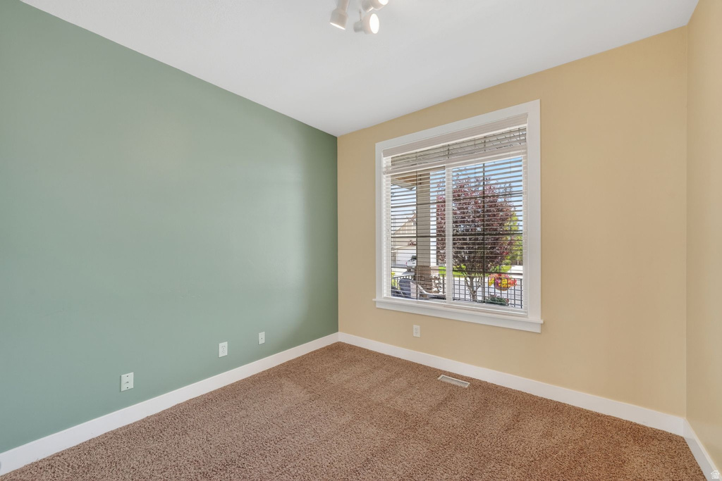 Room featuring a large window with white blinds, track lighting, and soft carpet flooring