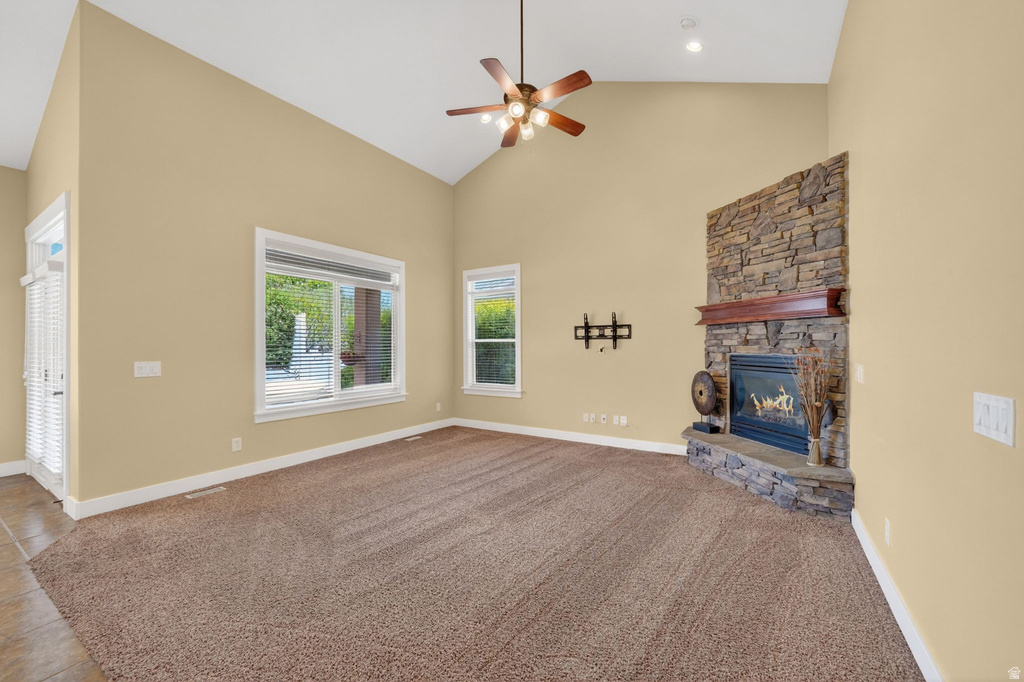 Spacious room featuring vaulted ceilings, a ceiling fan with integrated lighting, and carpet flooring
