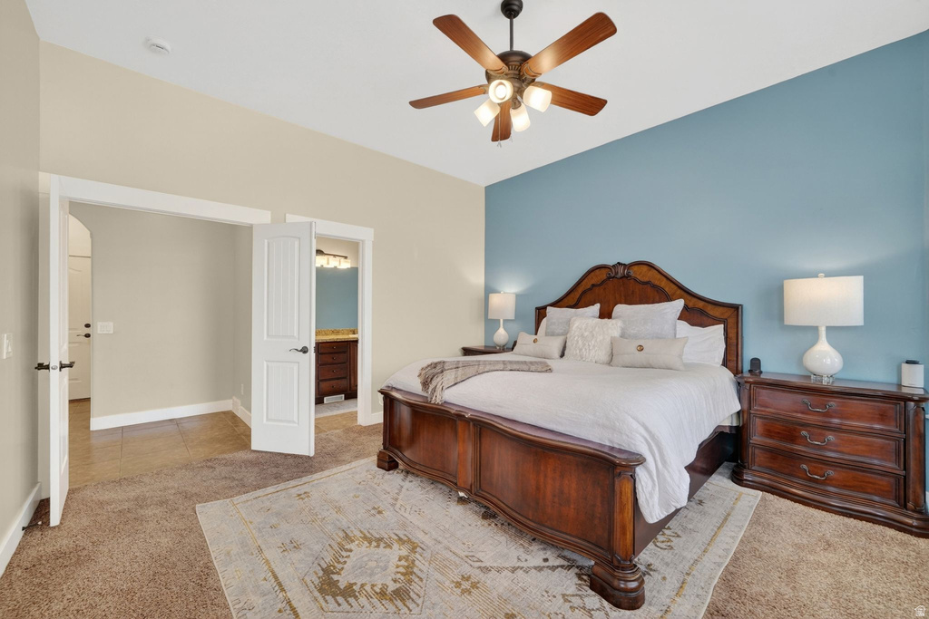 Carpeted bedroom featuring a vaulted ceiling and a wood-finish ceiling fan with integrated lighting