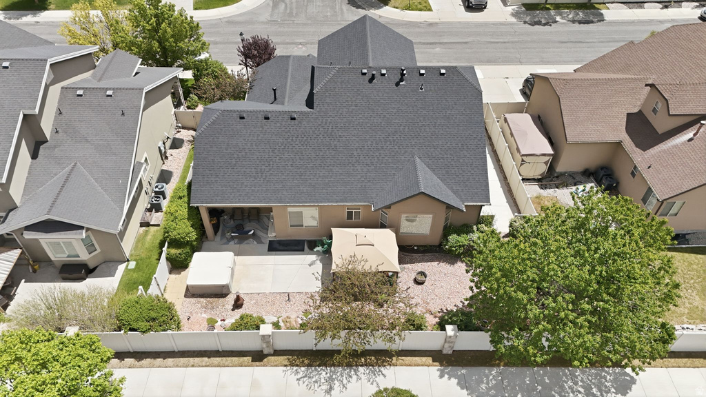 Private rear yard with a concrete patio, mature trees, and a stone-covered landscape bed