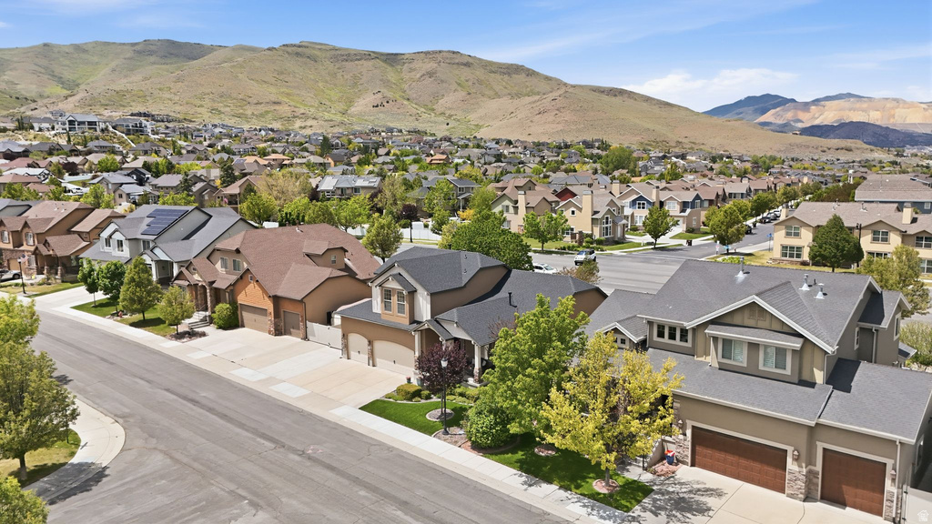 Residential neighborhood featuring a paved street, established landscaping, and mountain backdrop
