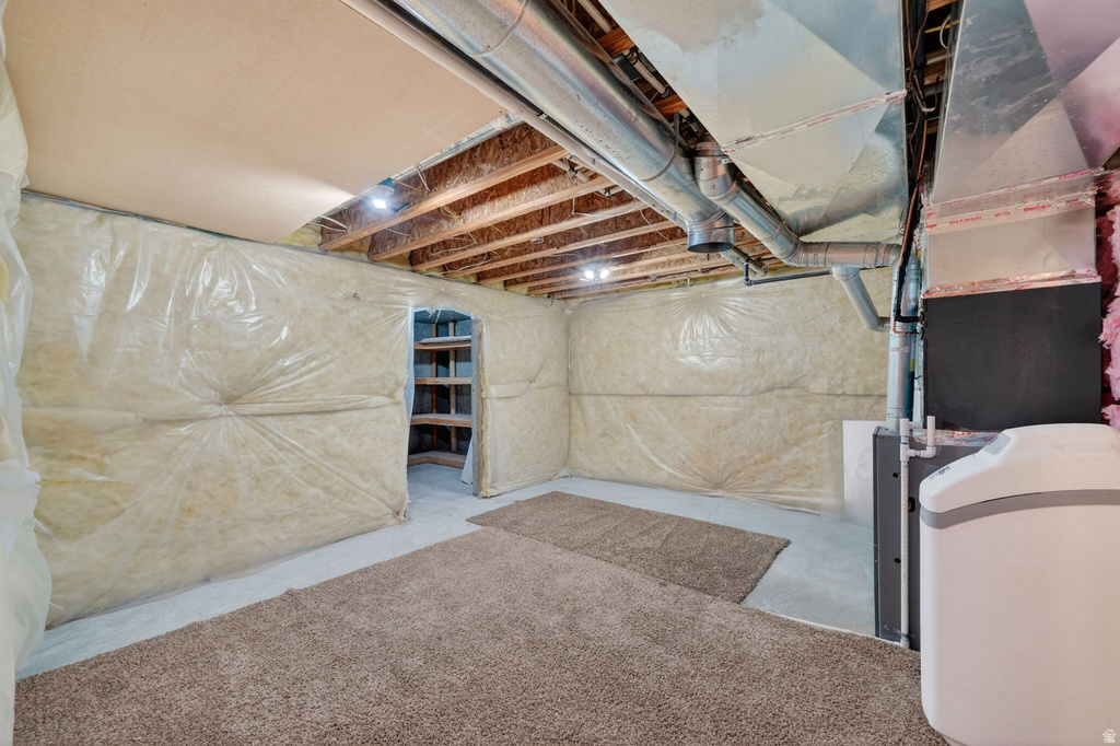 Partially finished basement featuring exposed ceiling joists, overhead ductwork, and insulation-wrapped walls