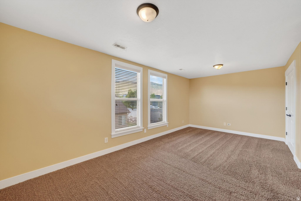 Spacious room featuring neutral tone walls, two prominent windows with blinds, and recessed lighting fixtures