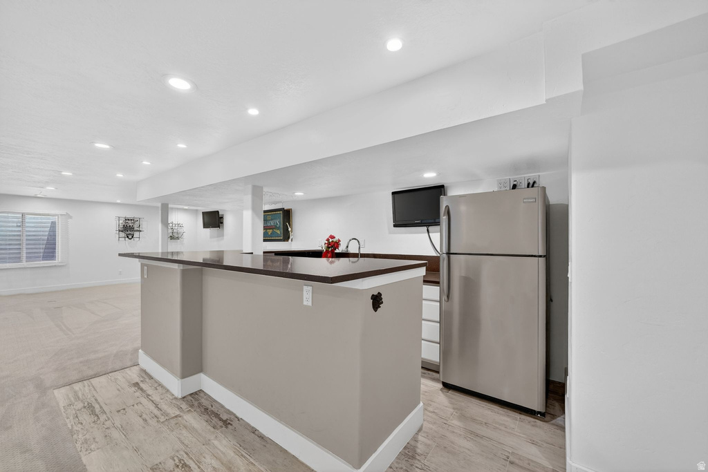 Lower-level entertainment space featuring a peninsula with a dark countertop and integrated sink