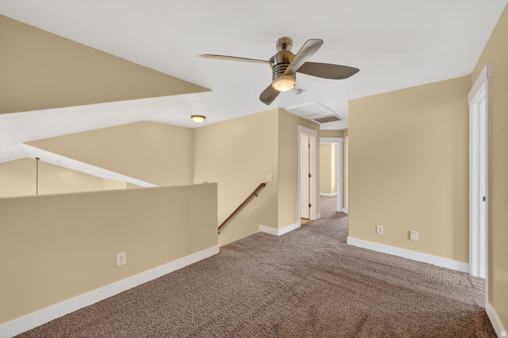 Upper landing featuring a ceiling fan, plush carpet, white trim, and a staircase with a wood handrail