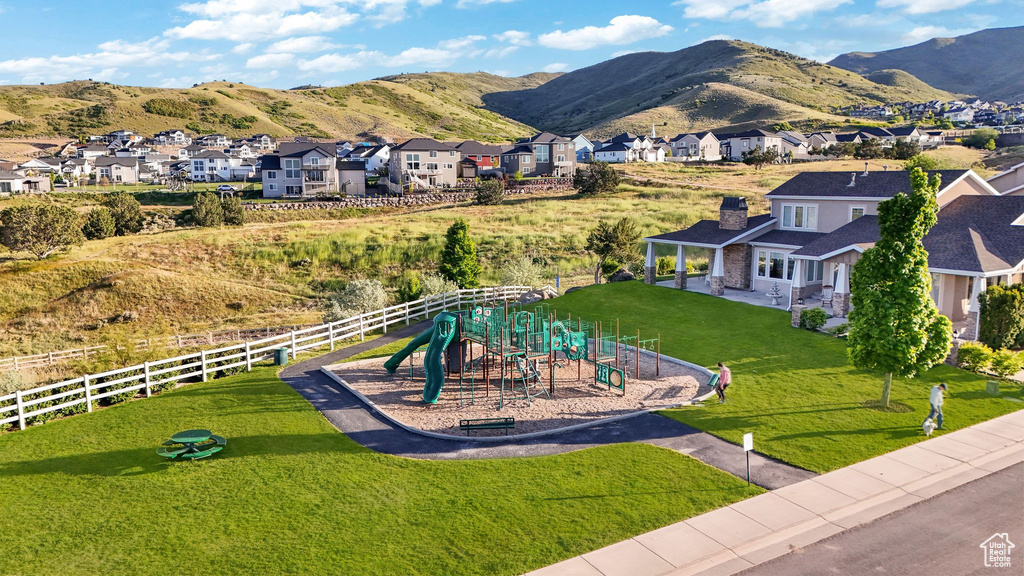 Community playground featuring multiple slides and climbing structures, bordered by a white picket fence