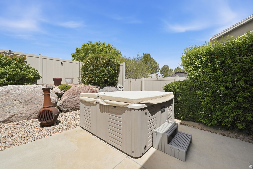 Outdoor spa with a light-colored cover and steps, set on a concrete patio