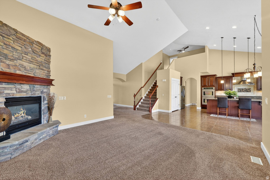 Spacious living area featuring vaulted ceilings and a stone-clad fireplace with a wood mantel