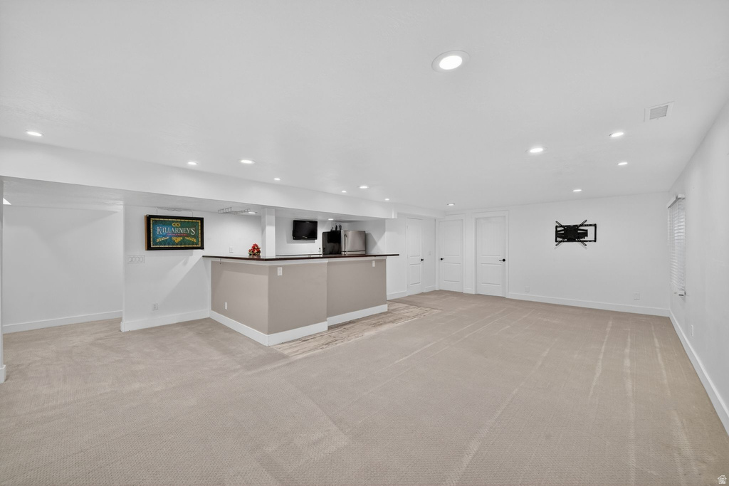 Expansive carpeted room featuring a built-in bar with a dark countertop, recessed lighting, and multiple white panel doors