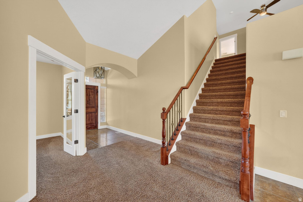 Entryway featuring a grand staircase with wood newel posts, wrought iron balusters, and carpeted treads