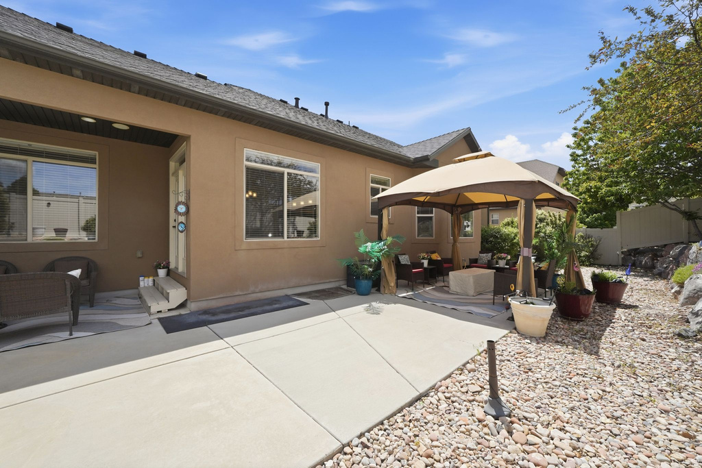 Spacious concrete patio with an adjacent gravel area and a mature tree