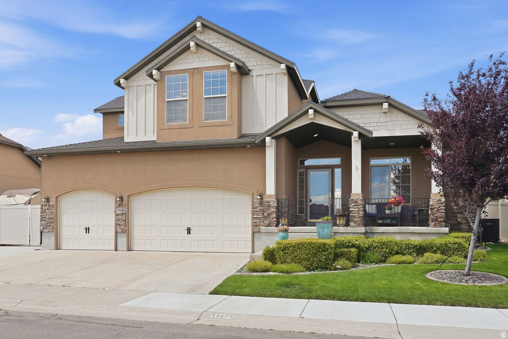 Two-story residence featuring a stucco and stone facade, covered front porch, and a two-car garage
