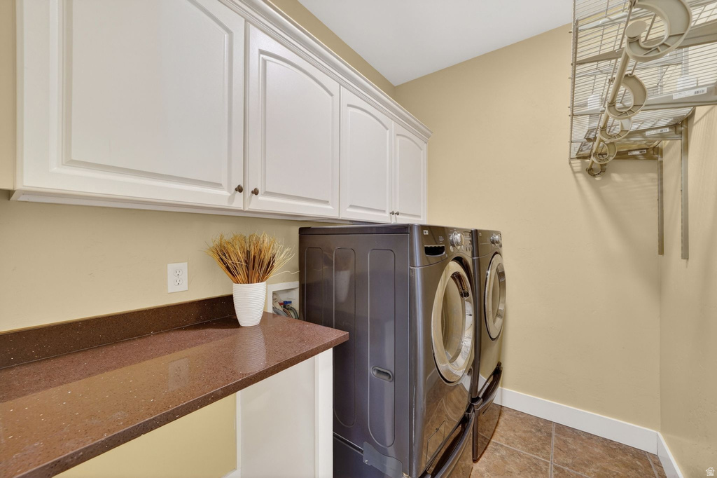 Laundry area featuring white upper cabinetry, a brown speckled countertop, and tiled flooring