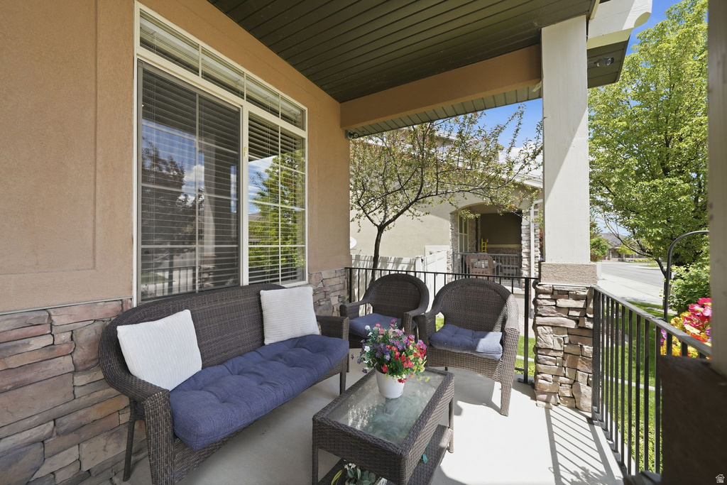 Covered porch featuring stucco exterior, stone veneer accents, grid-pattern windows, and a dark soffit ceiling