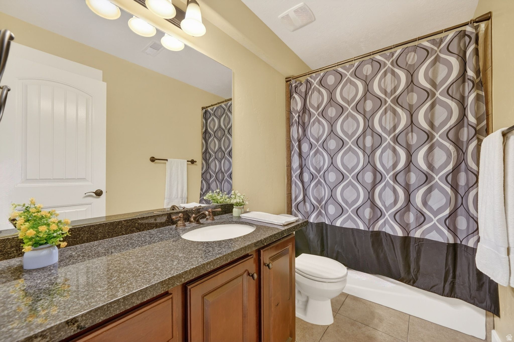Bathroom featuring a dark granite-finish countertop, undermount sink, and wood-finish cabinetry