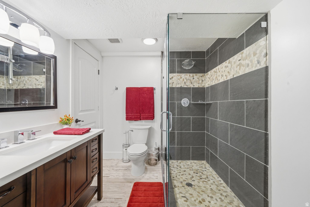Walk-in shower with clear glass enclosure, gray subway tile, and pebble stone accent