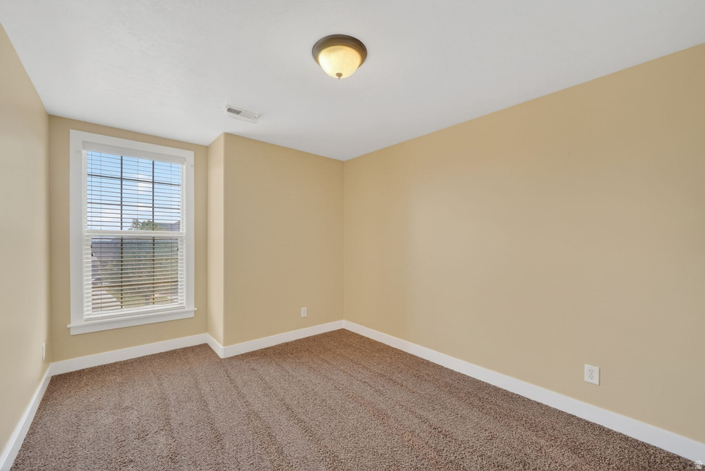 Carpeted room with a single window featuring blinds