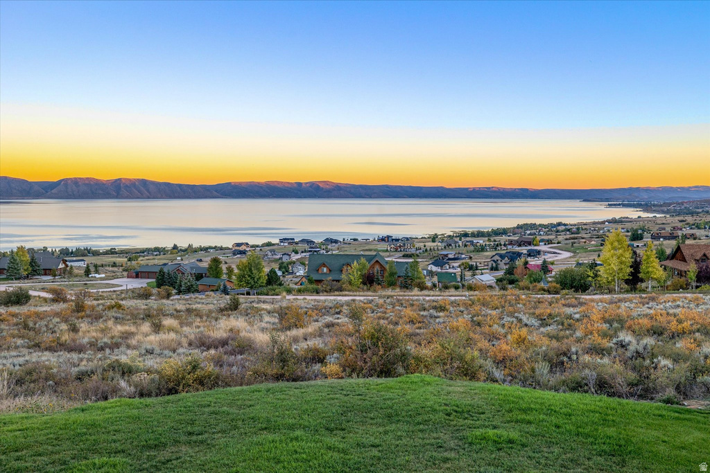 Expansive outdoor space featuring a manicured lawn, natural scrub brush, and distant homes