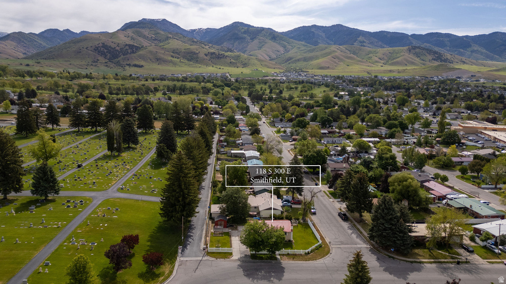Aerial perspective showcasing a residential property with surrounding green spaces and mountain backdrop