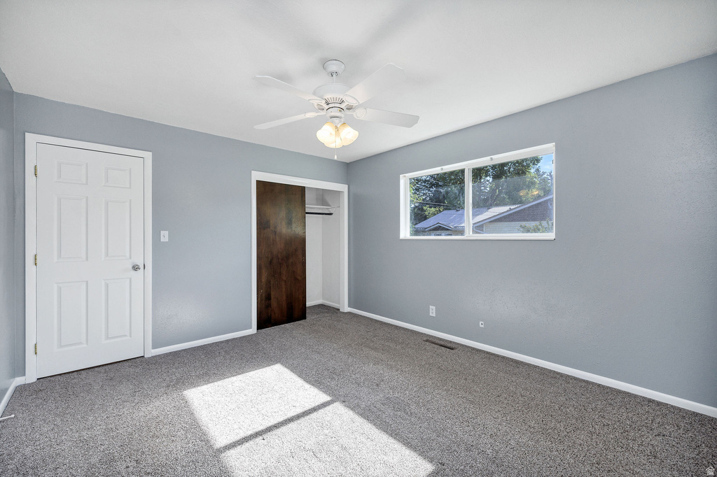 Bedroom featuring light gray walls, gray carpet, and a white ceiling fan with integrated lighting