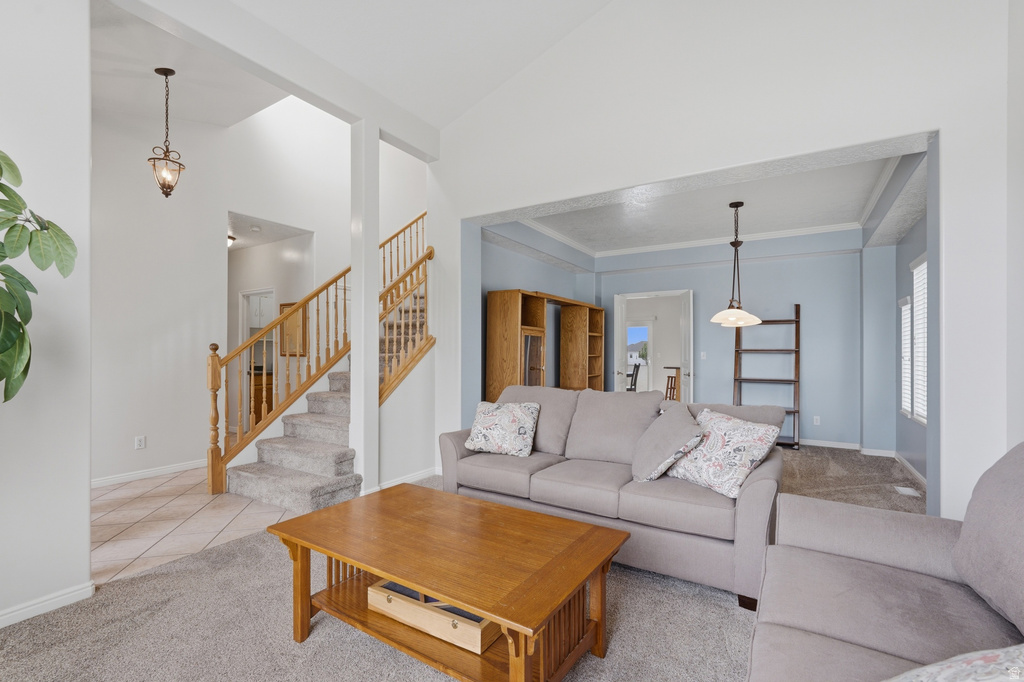 Expansive living area featuring vaulted ceilings, a carpeted staircase with wood railings, and a tiled entryway