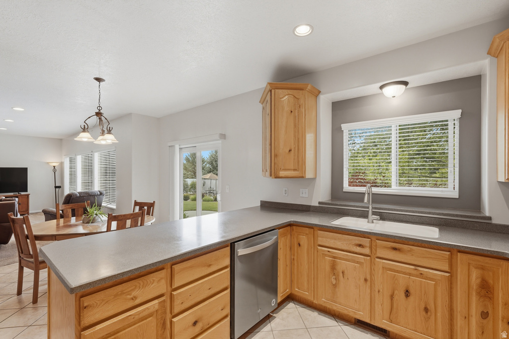 Kitchen featuring wood-finish cabinetry, light-toned countertops, and a stainless steel dishwasher