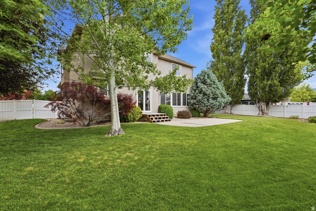 Expansive backyard featuring a manicured lawn, established perimeter fencing, and mature trees