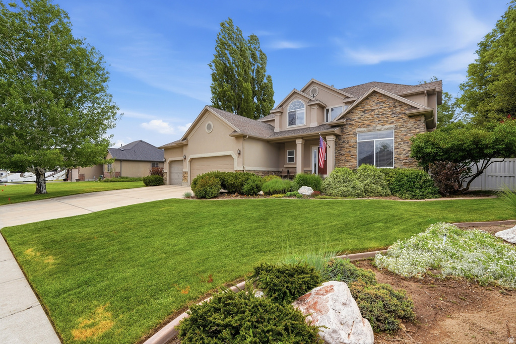 Stone and stucco exterior residence featuring a gabled roofline, multiple windows, and an attached two-car garage