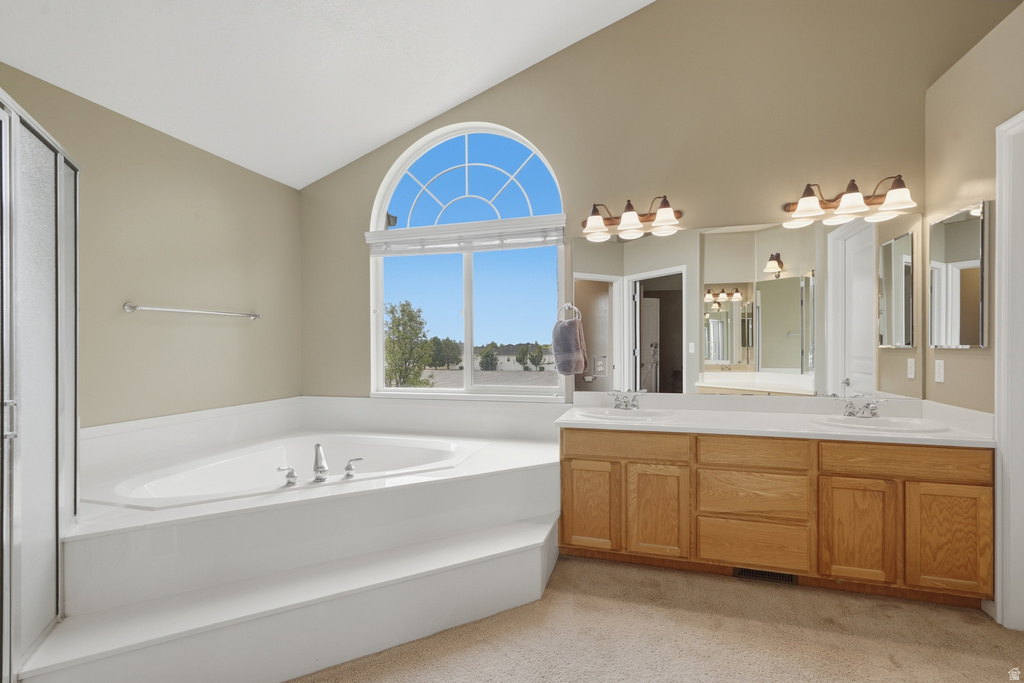 Spacious bath featuring a large soaking tub with tiered surround, a glass-enclosed shower, a dual-sink vanity with wood cabinetry, and an arched window