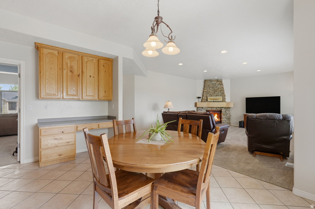 Open-concept living space featuring a stone-clad fireplace with a wood mantle, recessed lighting, and a built-in desk area with wood cabinetry