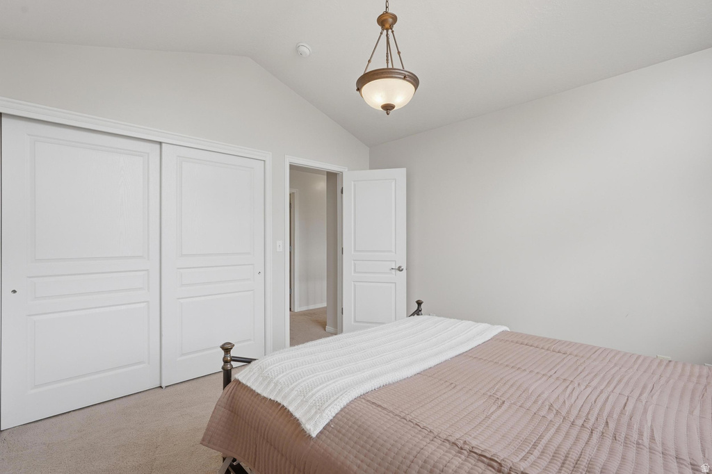 Vaulted ceiling room with neutral carpet flooring and white sliding closet doors