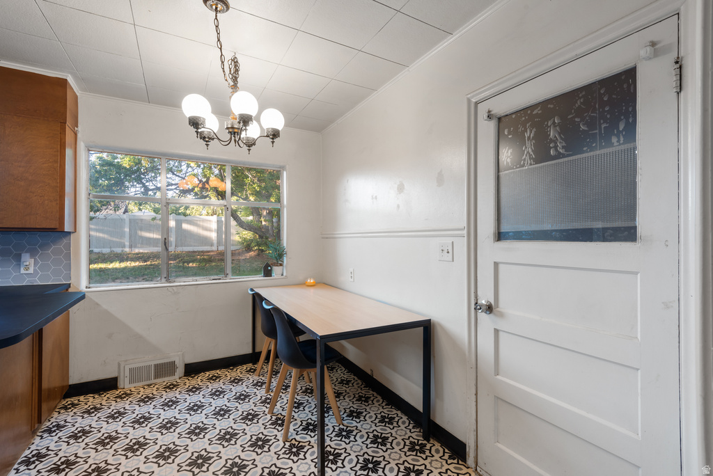 Kitchen area featuring patterned tile flooring, wood cabinetry with dark countertops, and a hexagonal tile backsplash