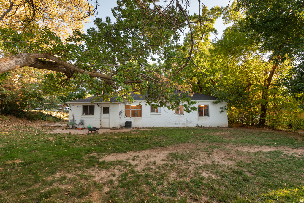 Rear exterior featuring white painted brick, multiple windows, and a back door opening to a grassy area