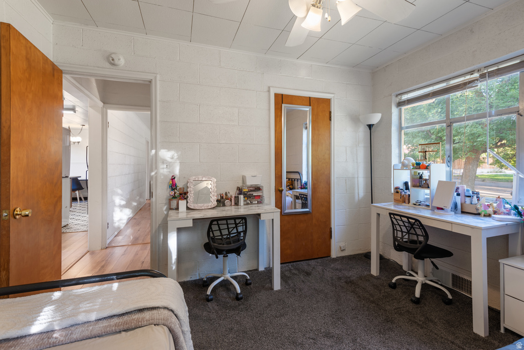 Carpeted interior space featuring white block walls and a ceiling fan