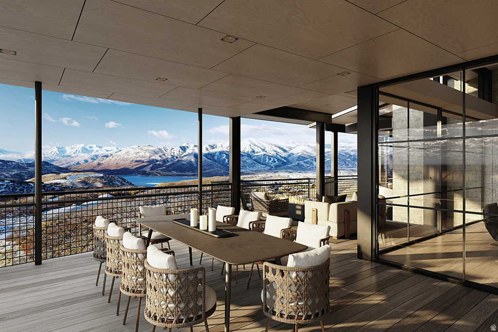 Expansive outdoor patio featuring a wood-finish deck, panoramic mountain and lake scenery, and a full-height glass wall