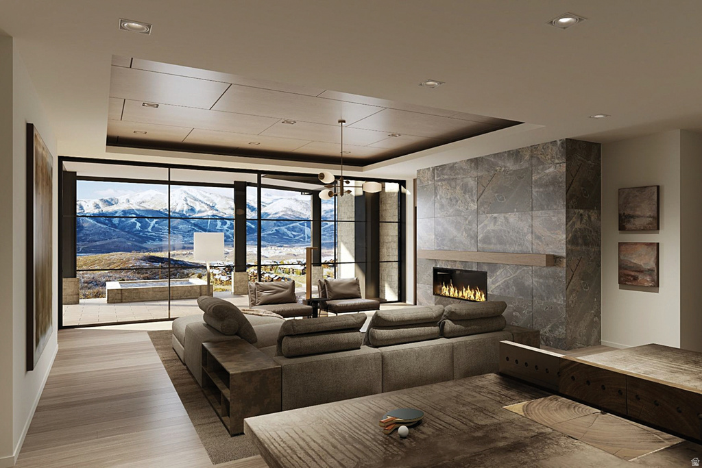 Expansive living area featuring floor-to-ceiling windows, a stone-clad fireplace with a wood mantel, wood-finish flooring, and recessed lighting